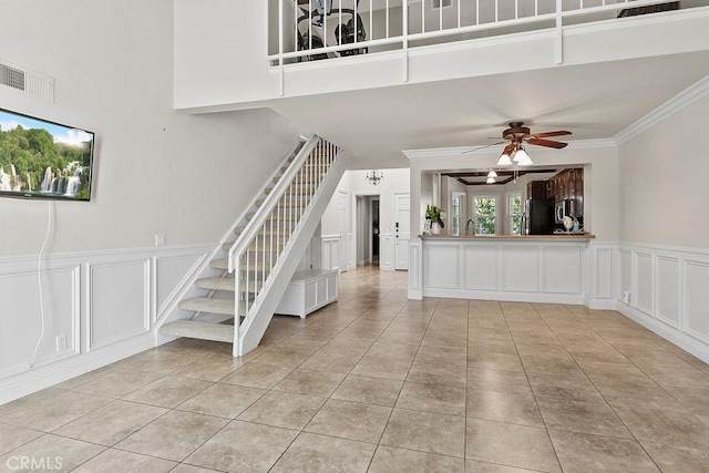 unfurnished living room featuring visible vents, stairs, a decorative wall, a ceiling fan, and light tile patterned floors