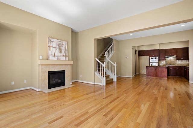 1703 Oconnor Ave, Chula Vista, CA 91913 - unfurnished living room featuring light wood-type flooring, stairs, and a tiled fireplace