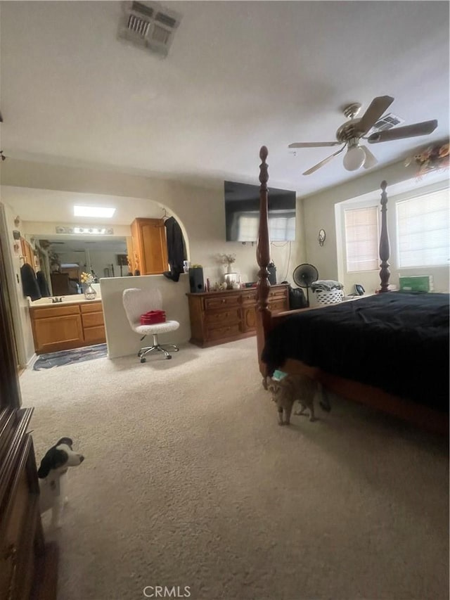 carpeted bedroom featuring visible vents, arched walkways, and ceiling fan