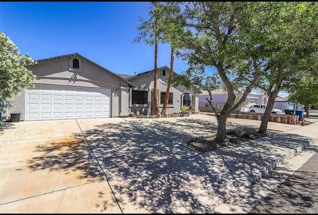 ranch-style home featuring an attached garage, stucco siding, and concrete driveway
