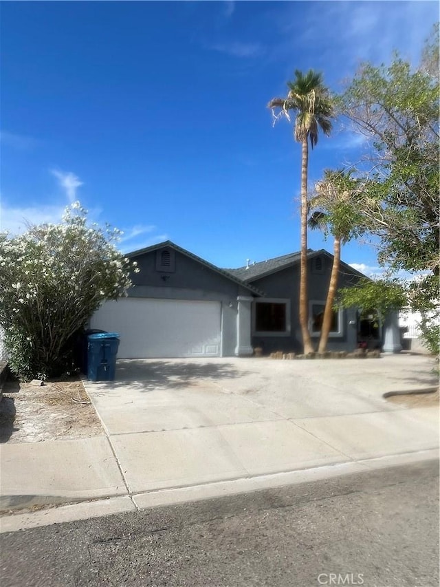 view of front of house featuring concrete driveway, an attached garage, and stucco siding