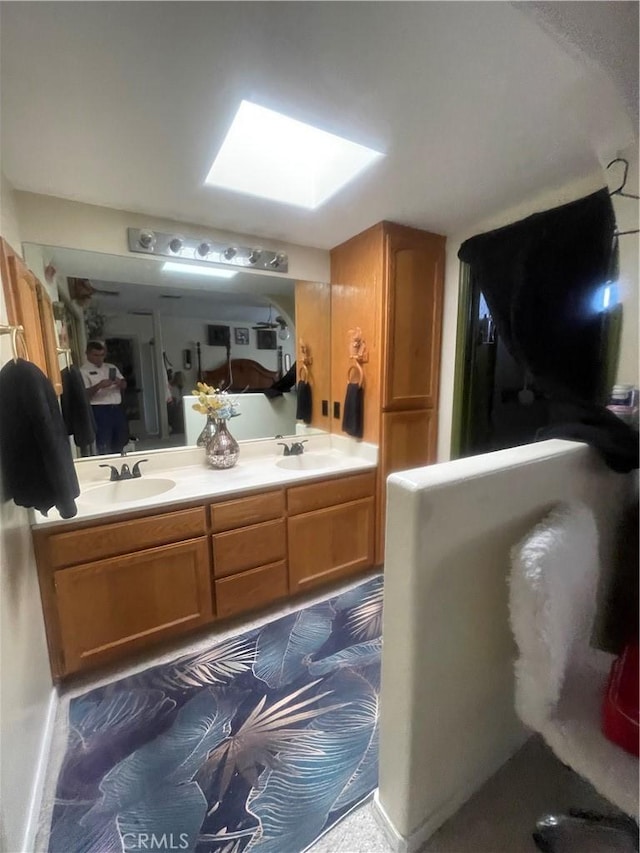 full bathroom featuring double vanity, a skylight, and a sink