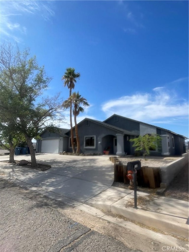 ranch-style home with a garage, stucco siding, and driveway