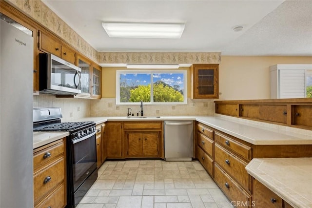 2132 El Dorado St, Los Osos, CA 93402 - kitchen with stone finish floor, brown cabinets, a sink, appliances with stainless steel finishes, and backsplash