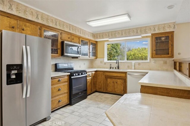 2132 El Dorado St, Los Osos, CA 93402 - kitchen featuring appliances with stainless steel finishes, brown cabinets, decorative backsplash, and glass insert cabinets