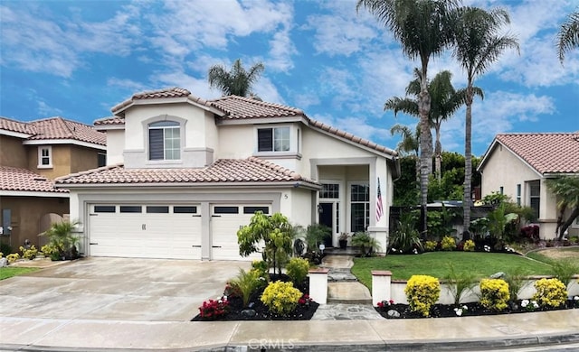mediterranean / spanish house featuring a tiled roof, driveway, a front lawn, an attached garage, and stucco siding