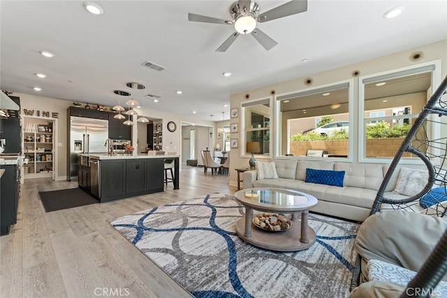 living area with visible vents, a ceiling fan, light wood-style floors, and recessed lighting