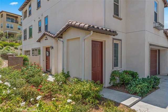 view of front of property featuring an attached garage, stucco siding, and a tiled roof