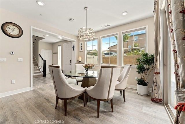 dining room featuring stairway, baseboards, an inviting chandelier, and light wood-style flooring