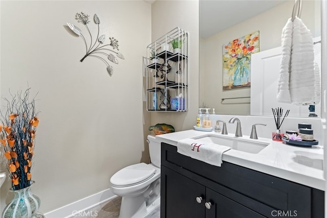 bathroom with toilet, baseboards, tile patterned floors, and vanity