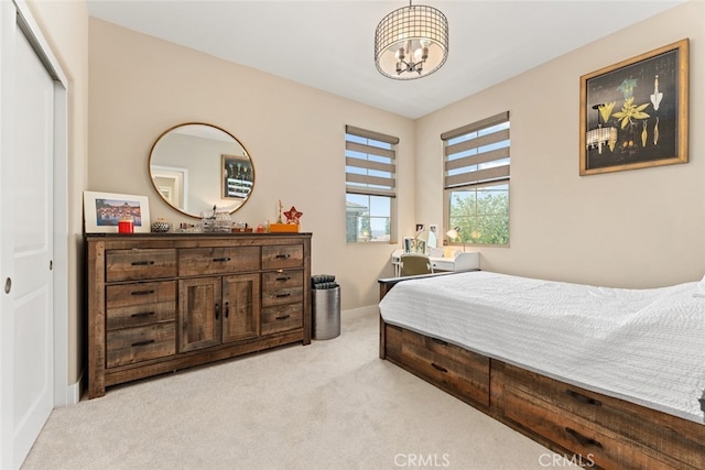 bedroom with light colored carpet, baseboards, and an inviting chandelier