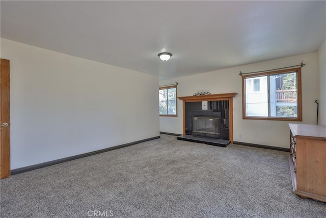 unfurnished living room with carpet floors, baseboards, and a fireplace