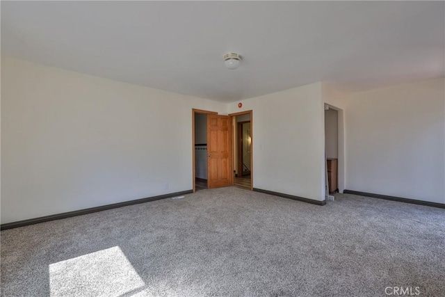 spare room with baseboards and carpet