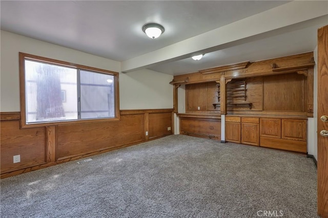 interior space with carpet, wainscoting, and wooden walls
