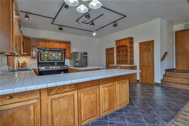 kitchen with open shelves, brown cabinets, rail lighting, a sink, and stainless steel appliances