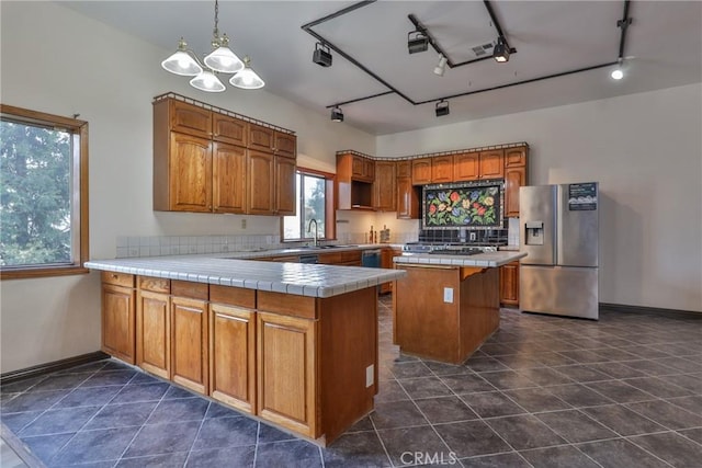 kitchen featuring stainless steel fridge with ice dispenser, brown cabinetry, a peninsula, and a chandelier