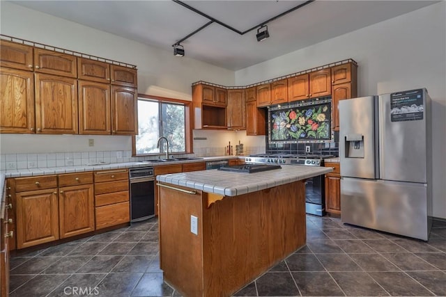 kitchen with brown cabinetry, a kitchen island, tile countertops, a sink, and stainless steel appliances