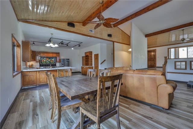 dining area featuring baseboards, lofted ceiling with beams, wood finished floors, and ceiling fan with notable chandelier