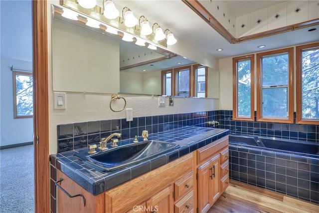 full bathroom with tiled tub, wood finished floors, and vanity
