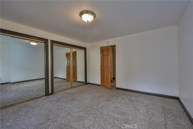 unfurnished bedroom featuring carpet floors, baseboards, and two closets