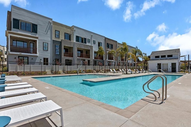 community pool featuring a patio, fence, and a residential view