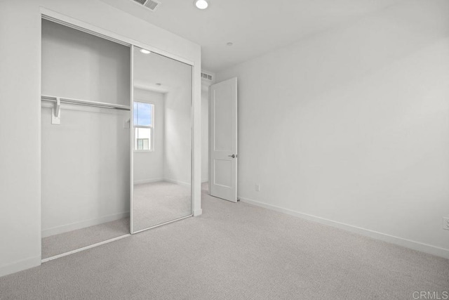 unfurnished bedroom with a closet, carpet floors, visible vents, baseboards, and recessed lighting