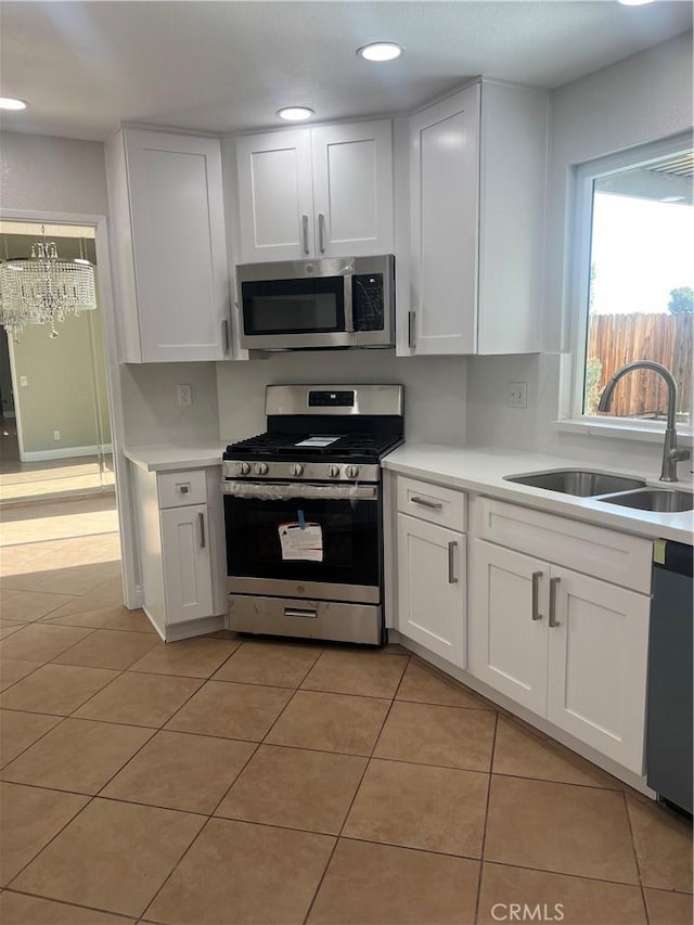 kitchen featuring light countertops, a sink, a notable chandelier, and stainless steel appliances