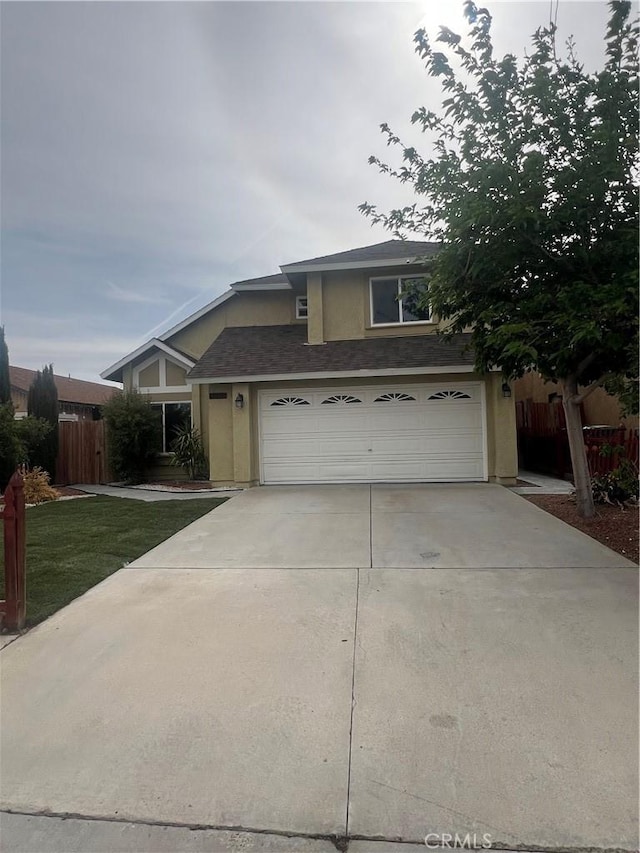 traditional-style house with fence, stucco siding, driveway, and a garage