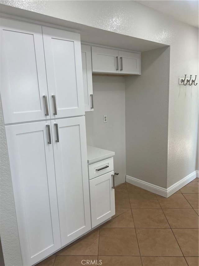 interior space featuring baseboards, a textured wall, and light tile patterned floors