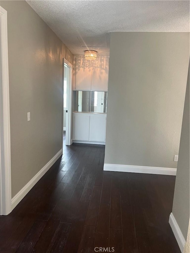 unfurnished room featuring baseboards, a textured ceiling, and dark wood finished floors