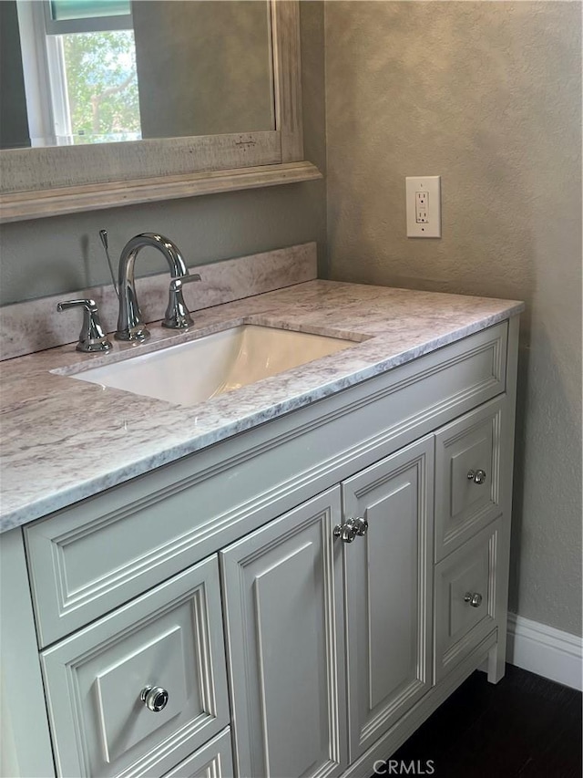 bathroom with vanity, baseboards, and a textured wall