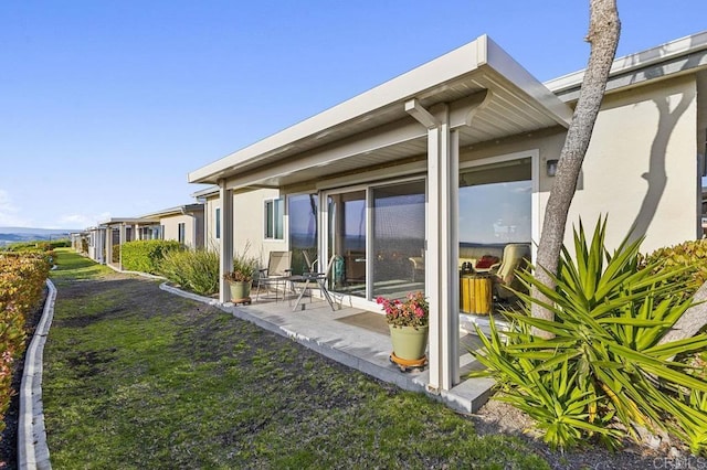 rear view of house featuring stucco siding and a patio area