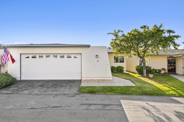 single story home with an attached garage, driveway, a front yard, and stucco siding