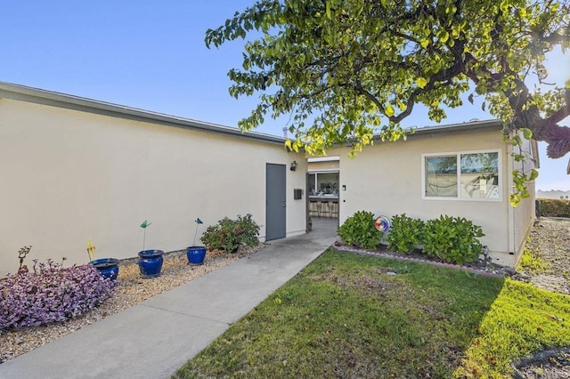 entrance to property with stucco siding and a yard
