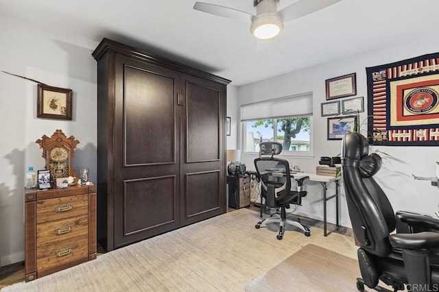 home office featuring light wood-type flooring, a ceiling fan, and baseboards