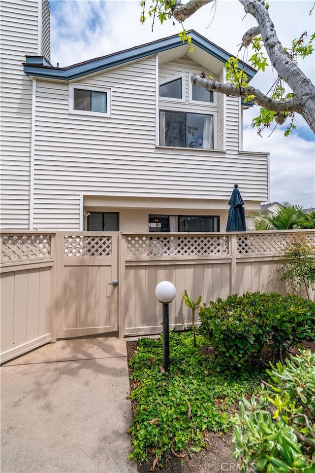 view of side of home featuring fence and a gate