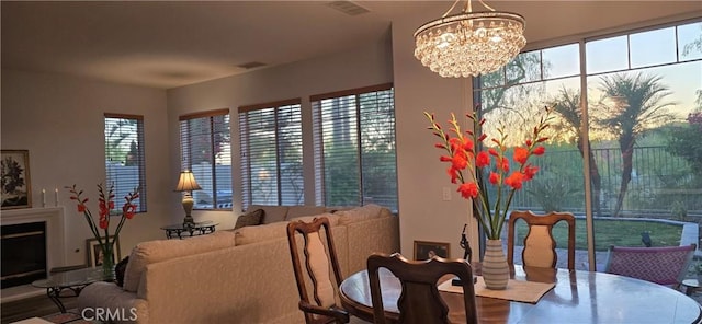 dining room featuring a fireplace, a notable chandelier, a healthy amount of sunlight, and visible vents
