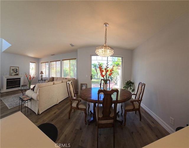 dining space with a wealth of natural light, dark wood-type flooring, baseboards, and a notable chandelier