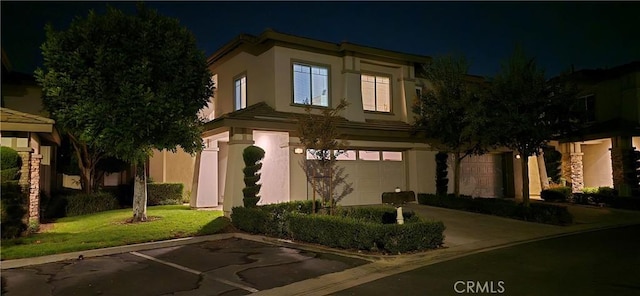 view of front of property featuring an attached garage, stucco siding, and a yard