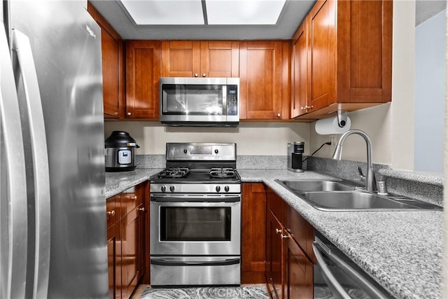 kitchen with a sink, light countertops, stainless steel appliances, and brown cabinets