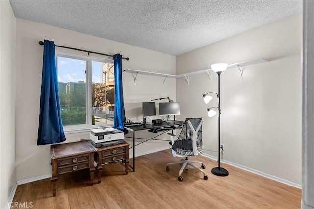 office featuring a textured ceiling, baseboards, and wood finished floors