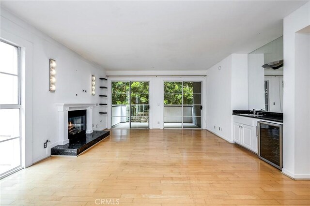 1401 S Bentley Ave Unit 203, Los Angeles, CA 90025 - unfurnished living room featuring beverage cooler, light wood-type flooring, and a glass covered fireplace
