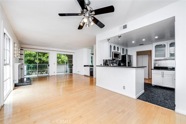 kitchen featuring stainless steel appliances, open floor plan, visible vents, and dark countertops