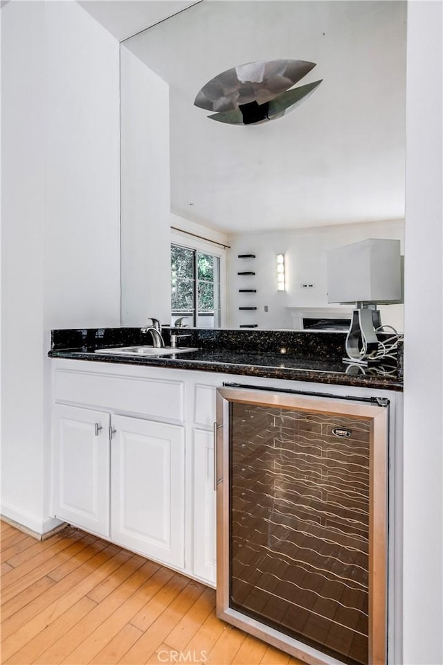 1401 S Bentley Ave Unit 203, Los Angeles, CA 90025 - kitchen featuring beverage cooler, a sink, white cabinets, light wood-type flooring, and dark stone countertops