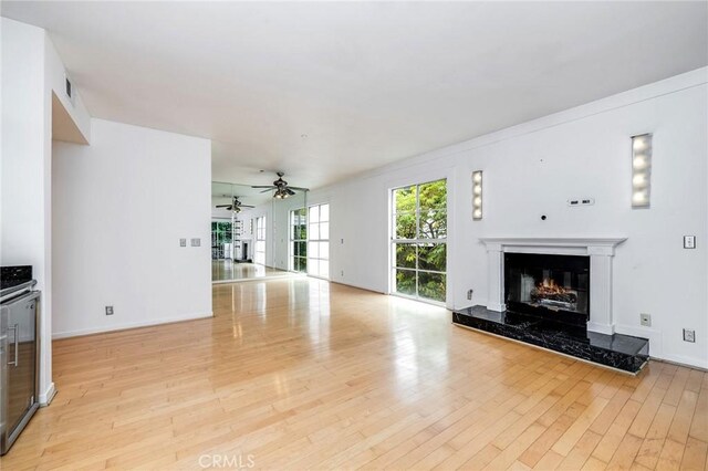 1401 S Bentley Ave Unit 203, Los Angeles, CA 90025 - unfurnished living room featuring ceiling fan, a premium fireplace, light wood-style floors, and baseboards