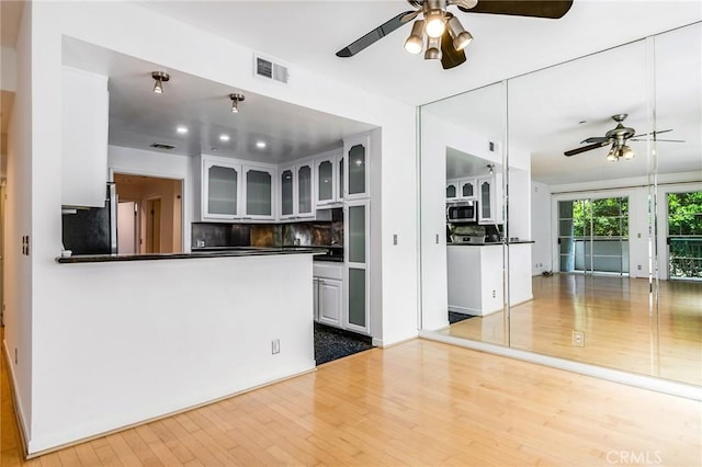 kitchen with a ceiling fan, visible vents, tasteful backsplash, wood finished floors, and stainless steel microwave