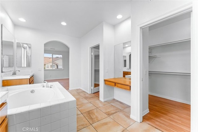 bathroom featuring a bath, vanity, baseboards, a spacious closet, and recessed lighting