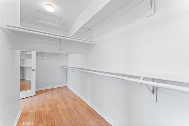 walk in closet with light wood-style flooring and attic access