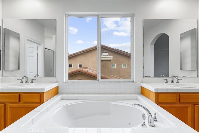 full bath with two vanities, a sink, and a garden tub