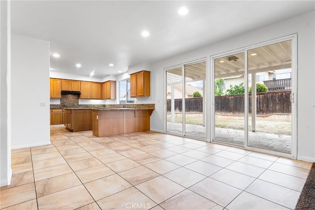 kitchen featuring light tile patterned floors, recessed lighting, brown cabinetry, and a peninsula